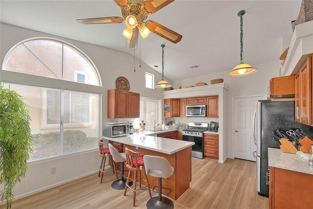 kitchen featuring pendant lighting, stainless steel appliances, a breakfast bar area, and a healthy amount of sunlight