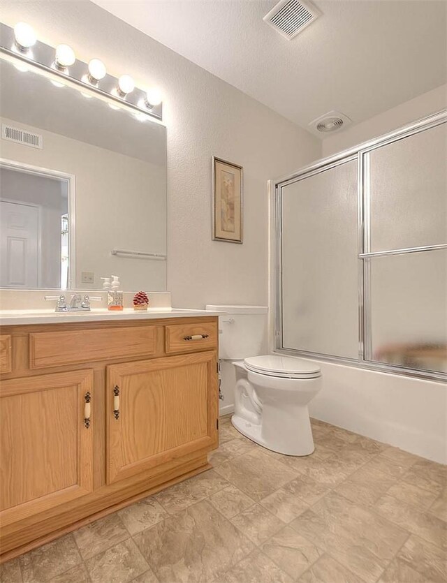 full bathroom featuring a textured ceiling, toilet, shower / bath combination with glass door, and vanity