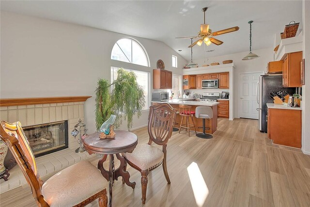 interior space with a fireplace, light wood-type flooring, lofted ceiling, and ceiling fan