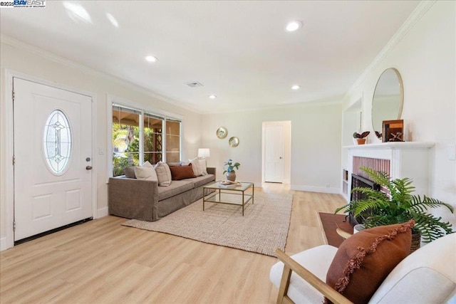 living room featuring a brick fireplace, ornamental molding, and light hardwood / wood-style flooring