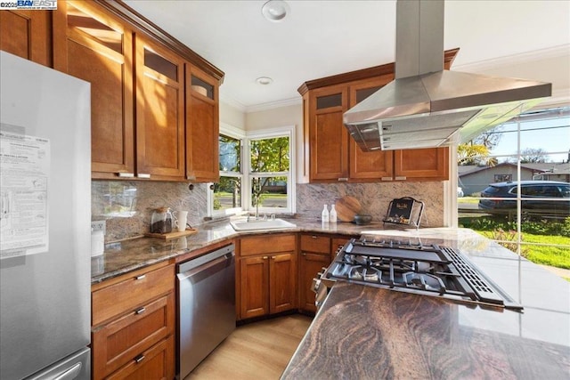 kitchen with sink, appliances with stainless steel finishes, island range hood, and dark stone countertops