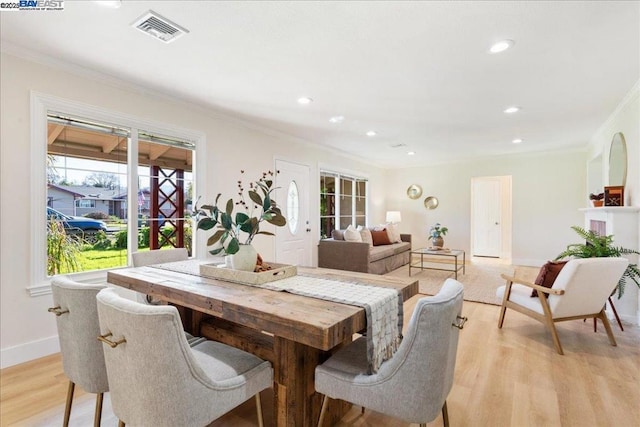 dining room featuring a healthy amount of sunlight, crown molding, and light hardwood / wood-style floors