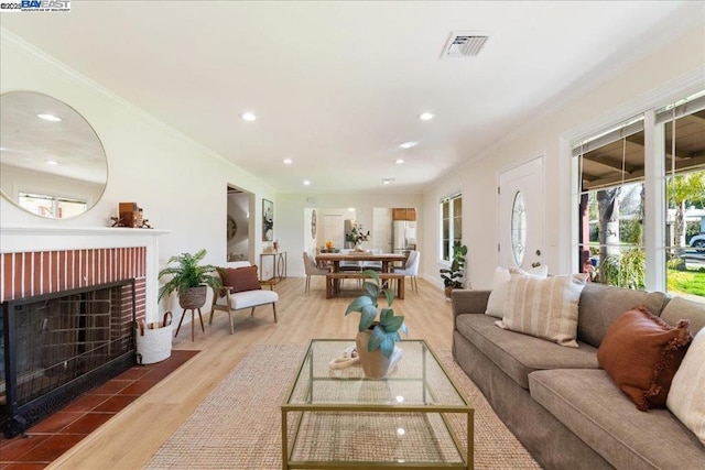 living room with a brick fireplace, crown molding, and hardwood / wood-style floors