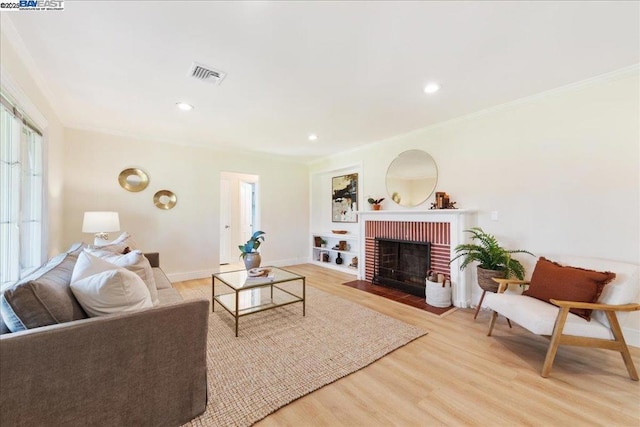 living room with a brick fireplace, hardwood / wood-style flooring, and ornamental molding