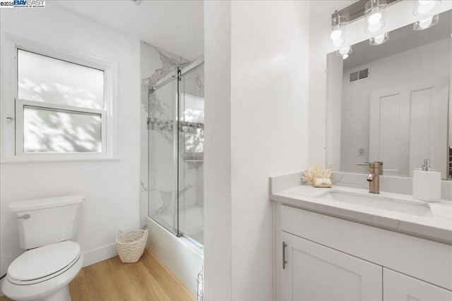 full bathroom with toilet, bath / shower combo with glass door, wood-type flooring, and vanity