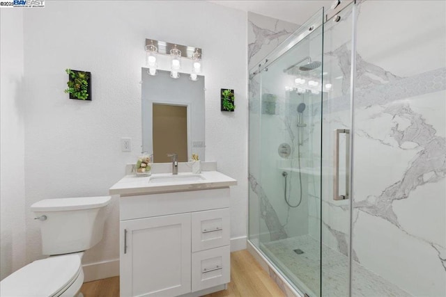 bathroom with toilet, a shower with shower door, hardwood / wood-style floors, and vanity