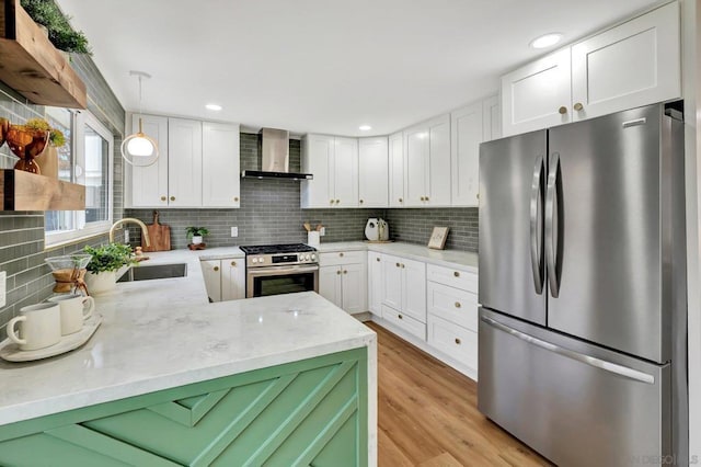 kitchen with white cabinets, wall chimney exhaust hood, appliances with stainless steel finishes, tasteful backsplash, and decorative light fixtures