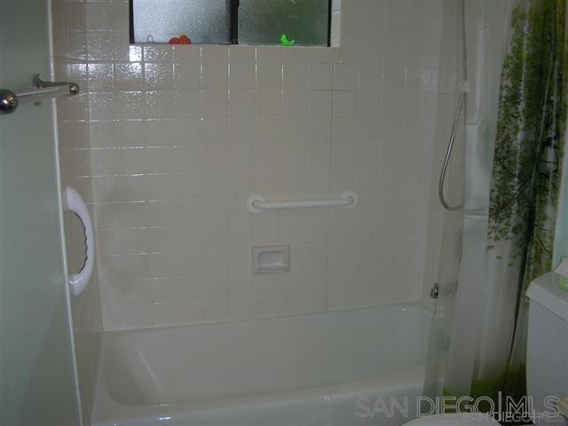 bathroom with shower / bath combo with shower curtain and toilet