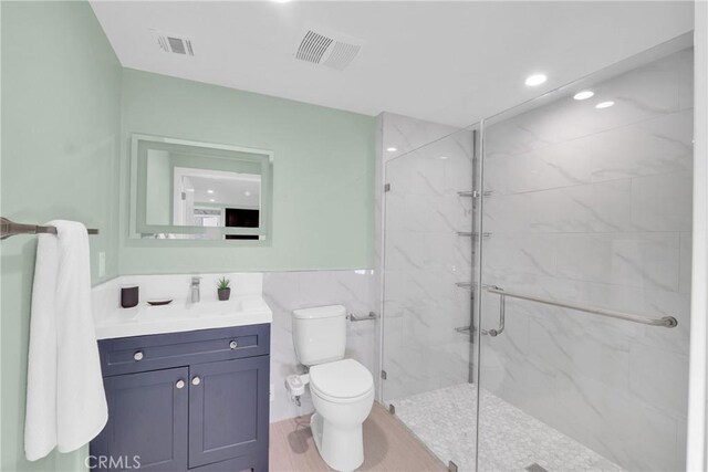 bathroom featuring an enclosed shower, vanity, tile walls, and toilet