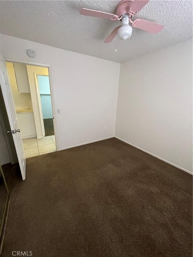 spare room featuring ceiling fan, carpet, and a textured ceiling