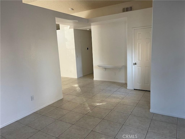 empty room featuring light tile patterned floors and a textured ceiling