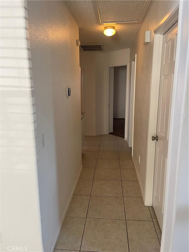 corridor with light tile patterned flooring and a textured ceiling