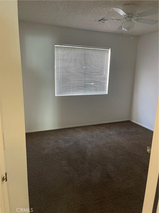 empty room featuring a textured ceiling and dark colored carpet