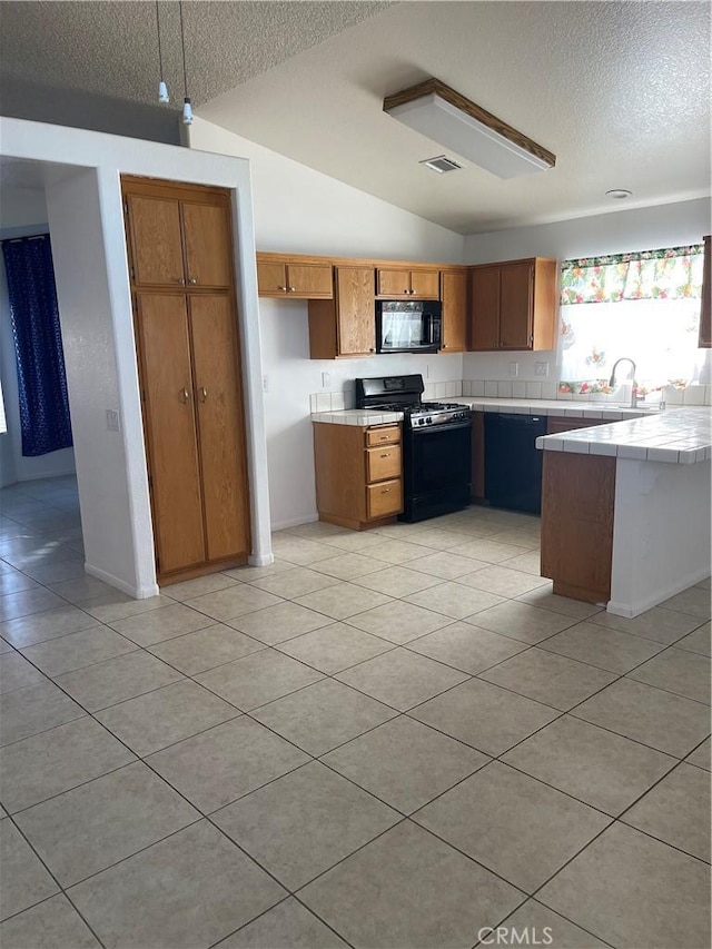 kitchen featuring vaulted ceiling, black appliances, a textured ceiling, tile counters, and light tile patterned floors