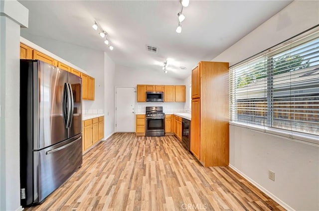 kitchen with vaulted ceiling, appliances with stainless steel finishes, and light wood-type flooring