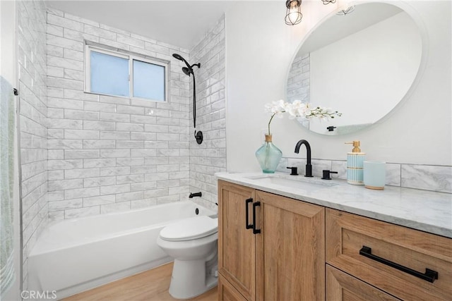 full bathroom with vanity, wood-type flooring, tiled shower / bath, and toilet