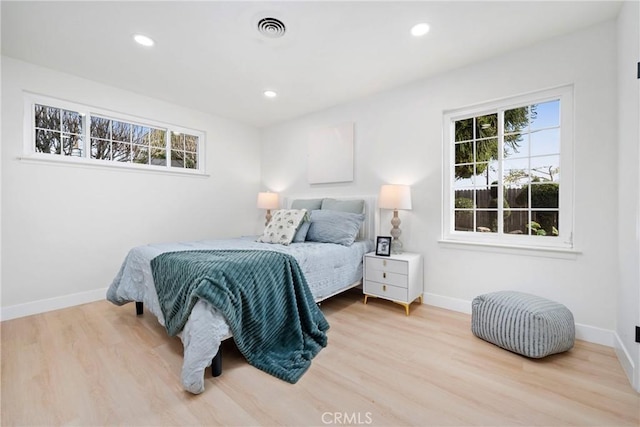 bedroom with multiple windows and light wood-type flooring