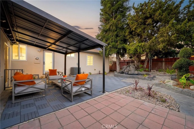 patio terrace at dusk with cooling unit and an outdoor living space