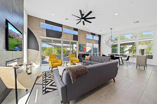 tiled living room with ceiling fan and a tiled fireplace