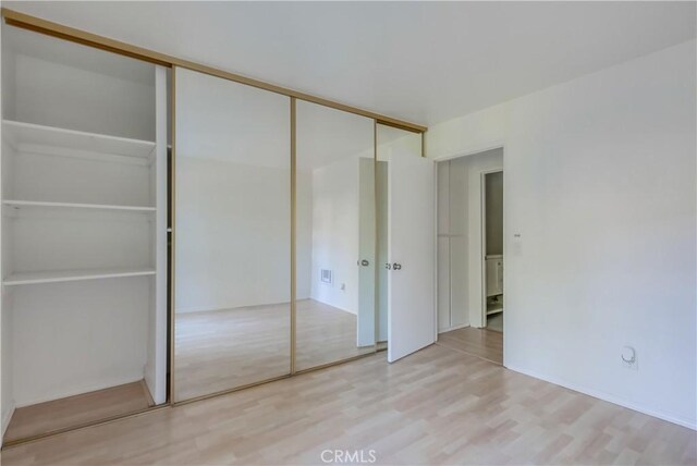 unfurnished bedroom featuring light wood-type flooring and a closet