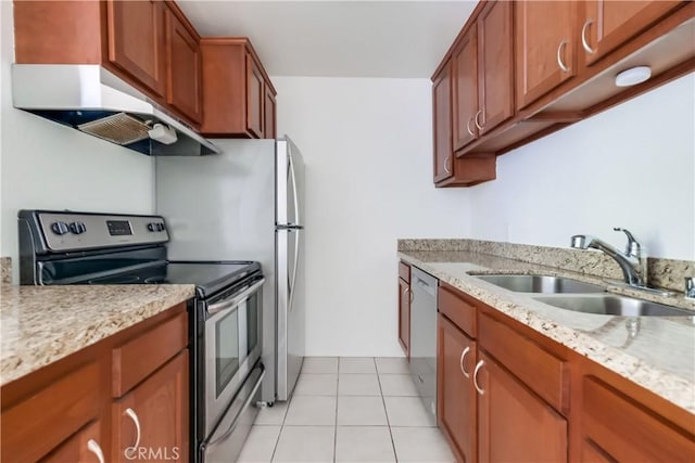 kitchen featuring brown cabinetry, under cabinet range hood, light tile patterned flooring, stainless steel appliances, and a sink