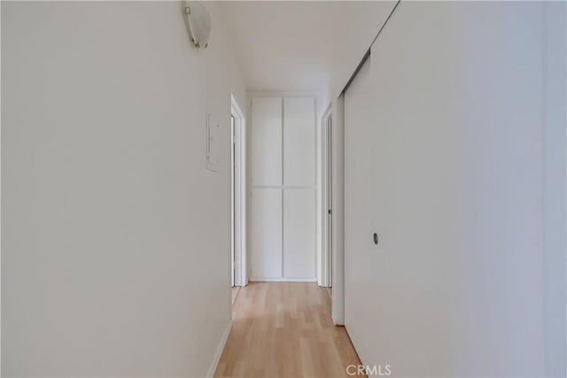 hall with light wood-style flooring and baseboards