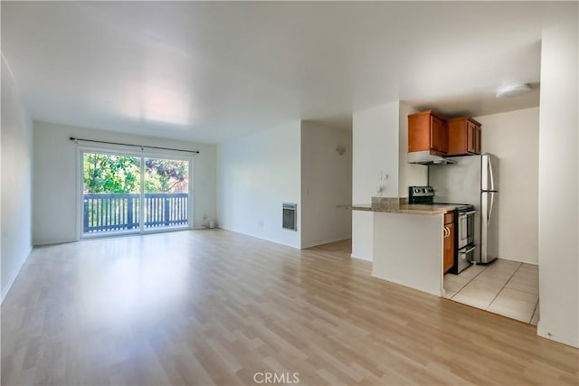 interior space with kitchen peninsula, electric stove, light stone counters, and light hardwood / wood-style flooring