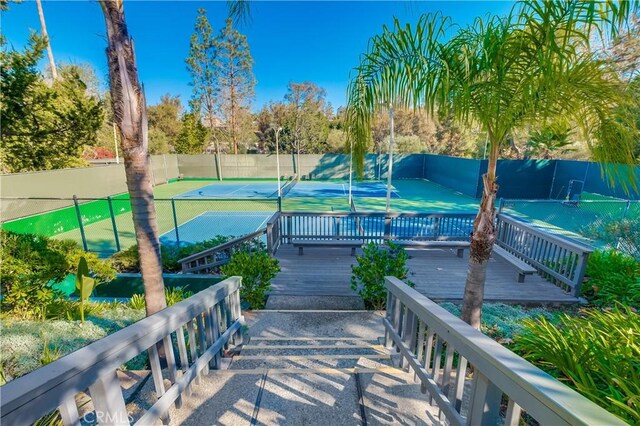 view of property's community with a wooden deck and tennis court