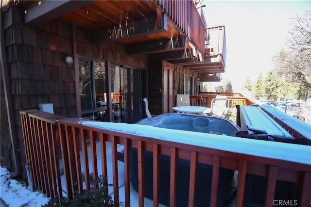 view of snowy exterior featuring a hot tub and a wooden deck