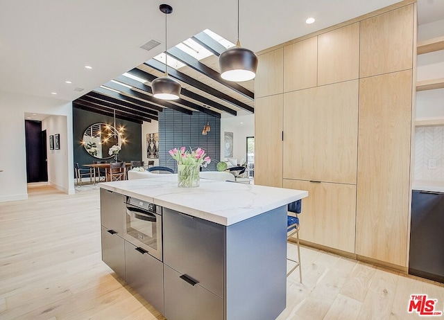 kitchen with light stone countertops, a kitchen island, hanging light fixtures, light hardwood / wood-style flooring, and beam ceiling