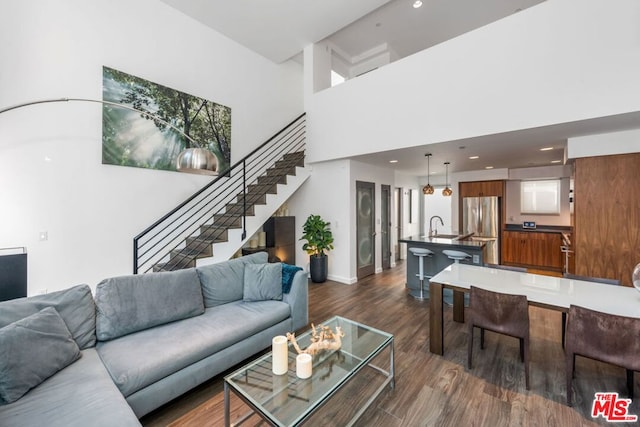 living room featuring dark hardwood / wood-style flooring, a towering ceiling, and sink