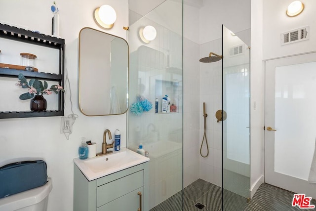 bathroom with toilet, vanity, and a tile shower