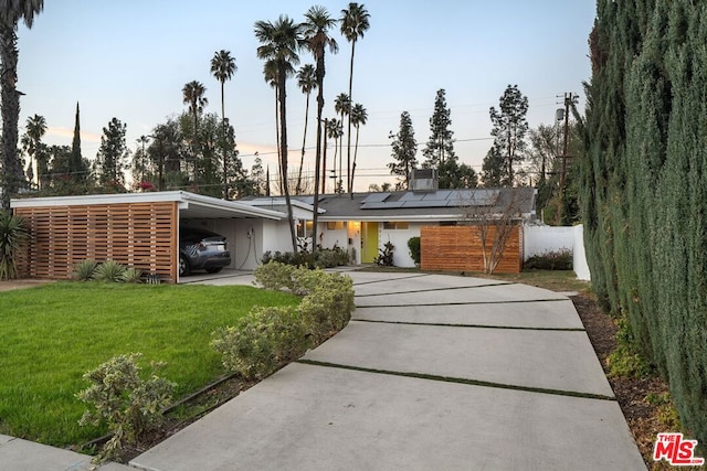 view of front of house with a lawn, a carport, and solar panels