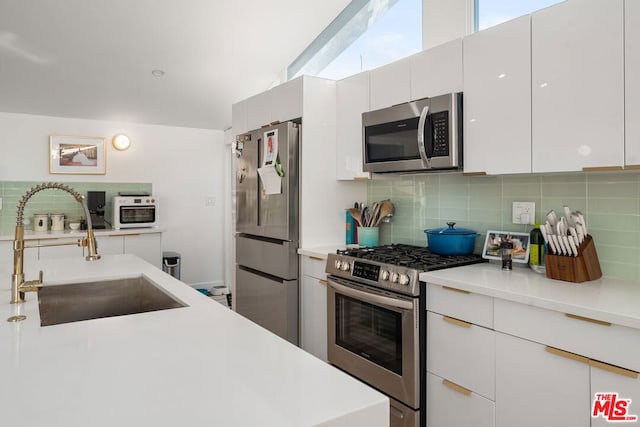 kitchen featuring plenty of natural light, stainless steel appliances, white cabinets, and sink