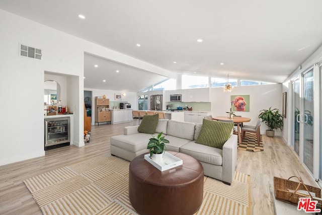 living room with high vaulted ceiling, beverage cooler, beamed ceiling, and light wood-type flooring