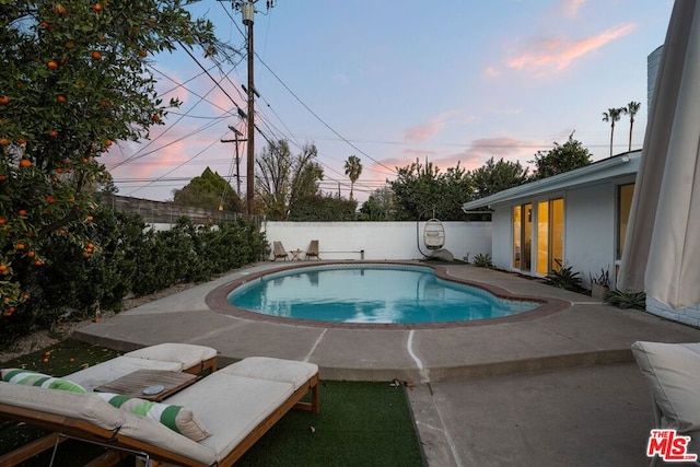 pool at dusk with a patio area