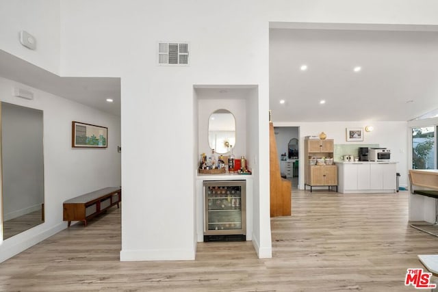 hall with beverage cooler and light hardwood / wood-style flooring