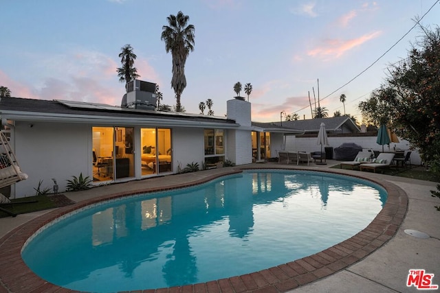 pool at dusk with a patio