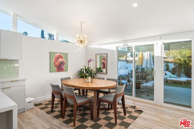 dining space with lofted ceiling, a chandelier, and light hardwood / wood-style flooring