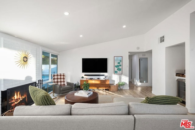 living room featuring lofted ceiling, light wood-type flooring, and beverage cooler