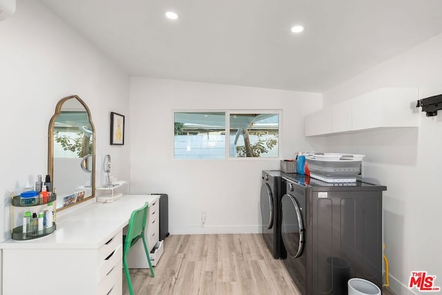 clothes washing area with cabinets, washer and dryer, and light hardwood / wood-style floors