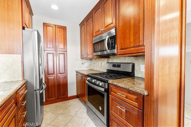 kitchen featuring light tile patterned floors, backsplash, light stone countertops, and stainless steel appliances