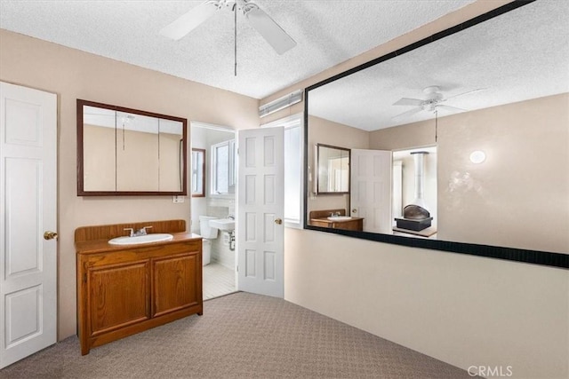 bathroom with ceiling fan, a textured ceiling, and vanity