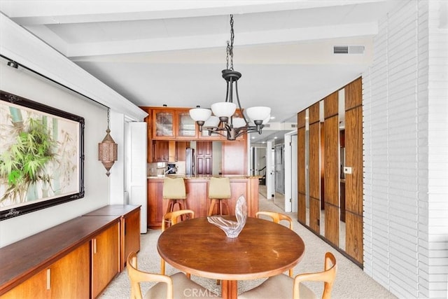 dining area featuring an inviting chandelier, light colored carpet, wood walls, and beamed ceiling