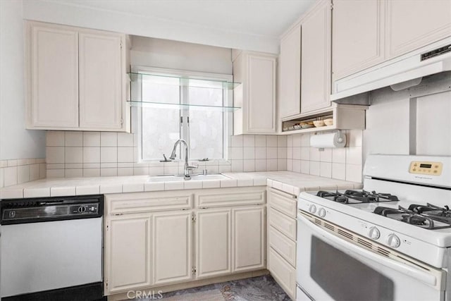 kitchen featuring sink, white appliances, white cabinets, and tile counters