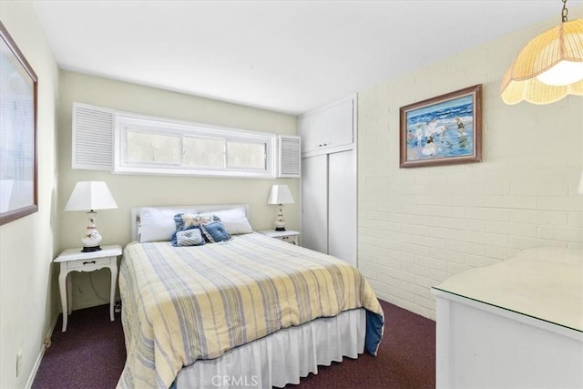 bedroom featuring dark carpet and brick wall