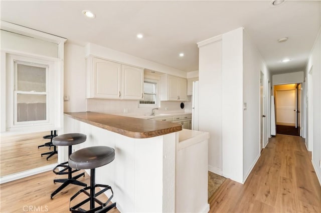 kitchen with light wood-style floors, white cabinetry, a breakfast bar, and recessed lighting