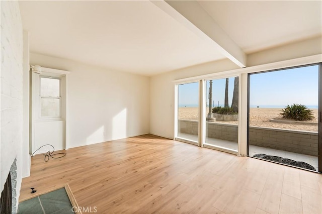 spare room featuring beamed ceiling and wood finished floors