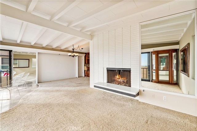 unfurnished living room with lofted ceiling with beams, a fireplace, carpet flooring, and an inviting chandelier