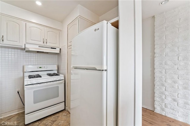 kitchen featuring white appliances, white cabinets, decorative backsplash, light wood-style flooring, and under cabinet range hood